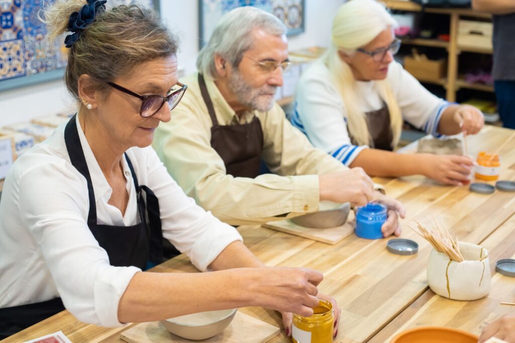 Plusieurs personnes âgées assises autour d'une table préparent un travail manuel