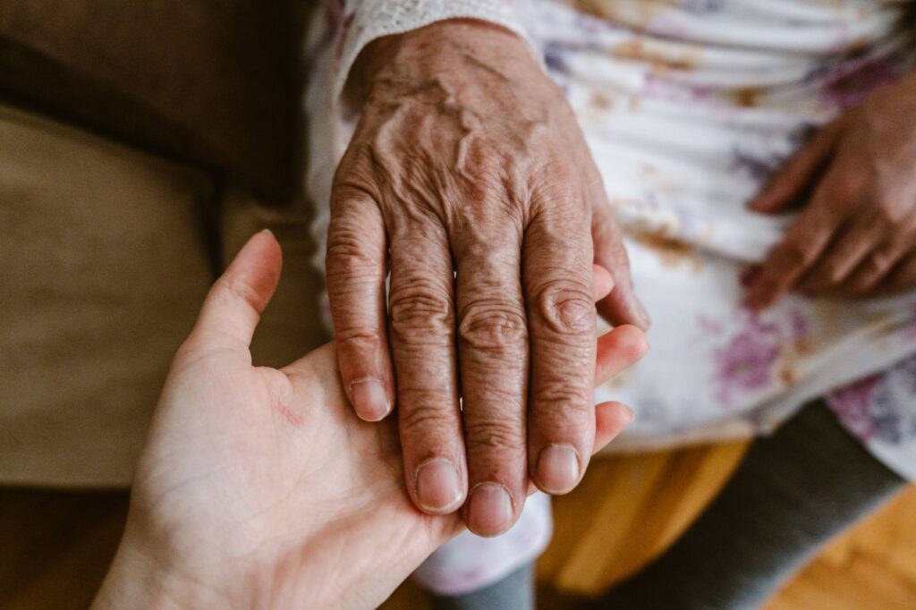 Une main jeune pose délicatement sur la main ridée d'une personne âgée